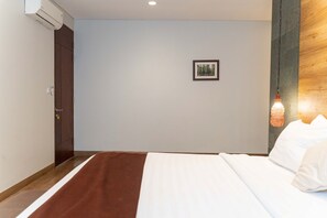 A hotel room with a bed, a door, a picture on the wall, and a wooden panel on the right side. - Atsuka Hill View 8BR Vila with Private Heated Pool (Cimenyan)