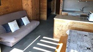 A compact living space with a sofa, a wooden wardrobe, a kitchenette, and a patterned rug. - 200m from ski slopes, 4th floor, tv, 31m², Val Thorens (Val Thorens)