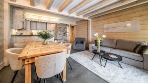 Un intérieur moderne avec une table à manger en bois, des chaises rembourrées, un canapé gris et un tapis blanc.
