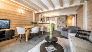Un salon moderne avec un plafond en bois, un coin repas avec une table et des chaises en bois, et un espace salon confortable avec un canapé et une table basse.