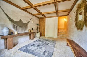 A room with a wooden bench, a woven hanging chair, a patterned rug, and a staircase leading to another area. - Lumina at LOSANTOS Tulum (Tulum)
