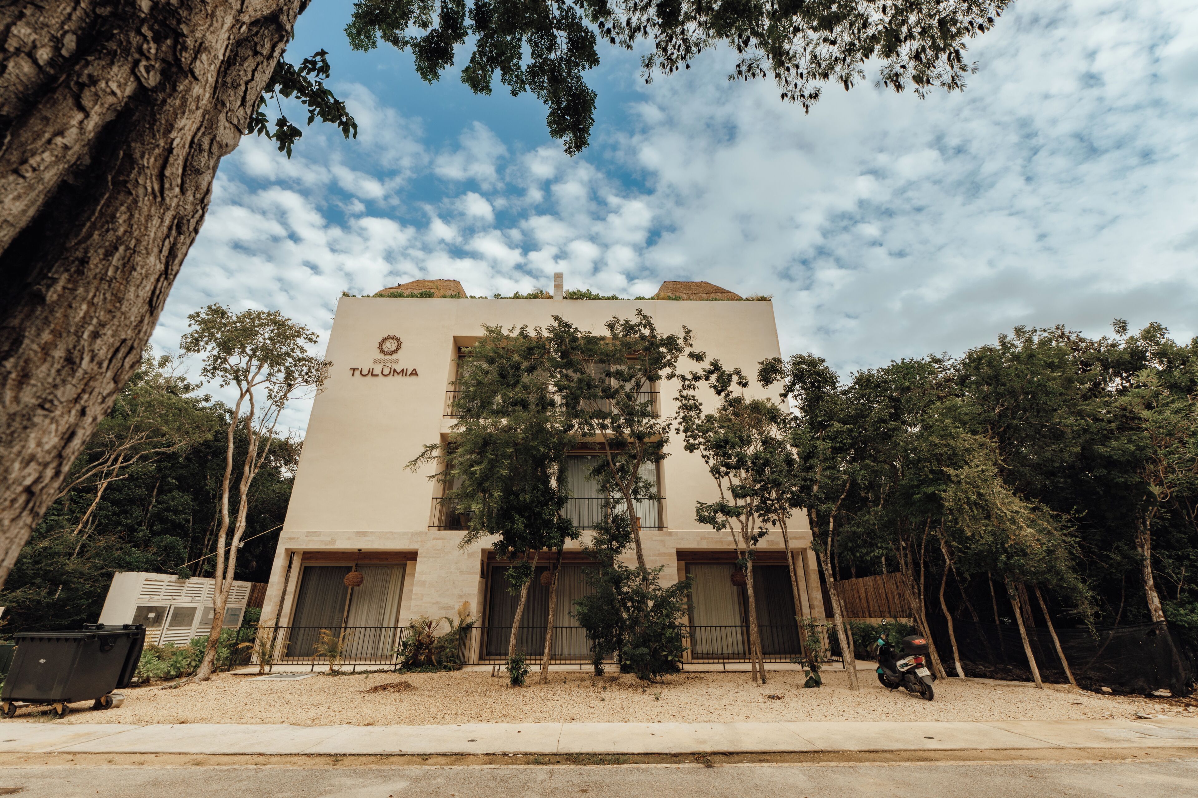 Un edificio llamado 'Tulumia' con fachada color beige, múltiples ventanas y una entrada porticada.