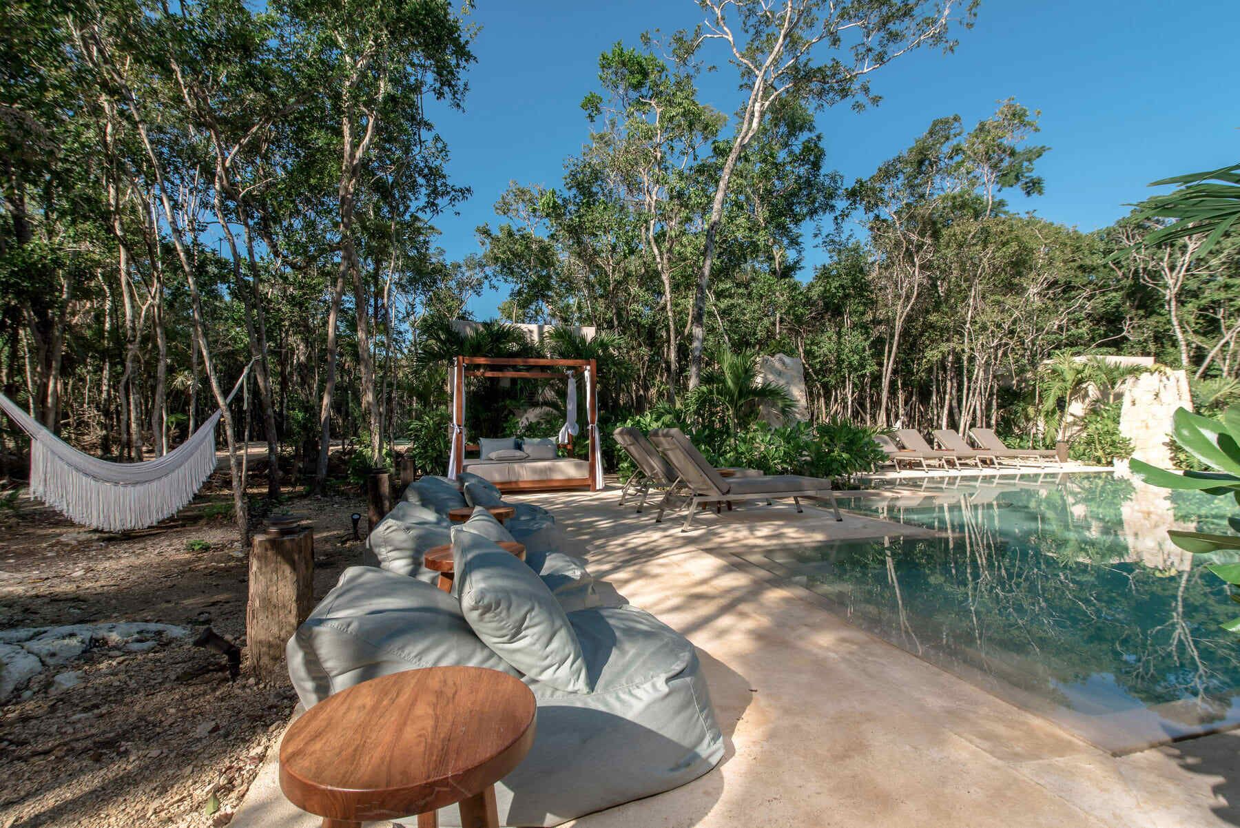 A pool area with lounge chairs, a hammock, and a wooden deck.