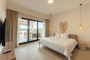 A hotel room with a bed, a TV, a desk, a chair, and a balcony with a view. - Lumina at LOSANTOS Tulum (Tulum)