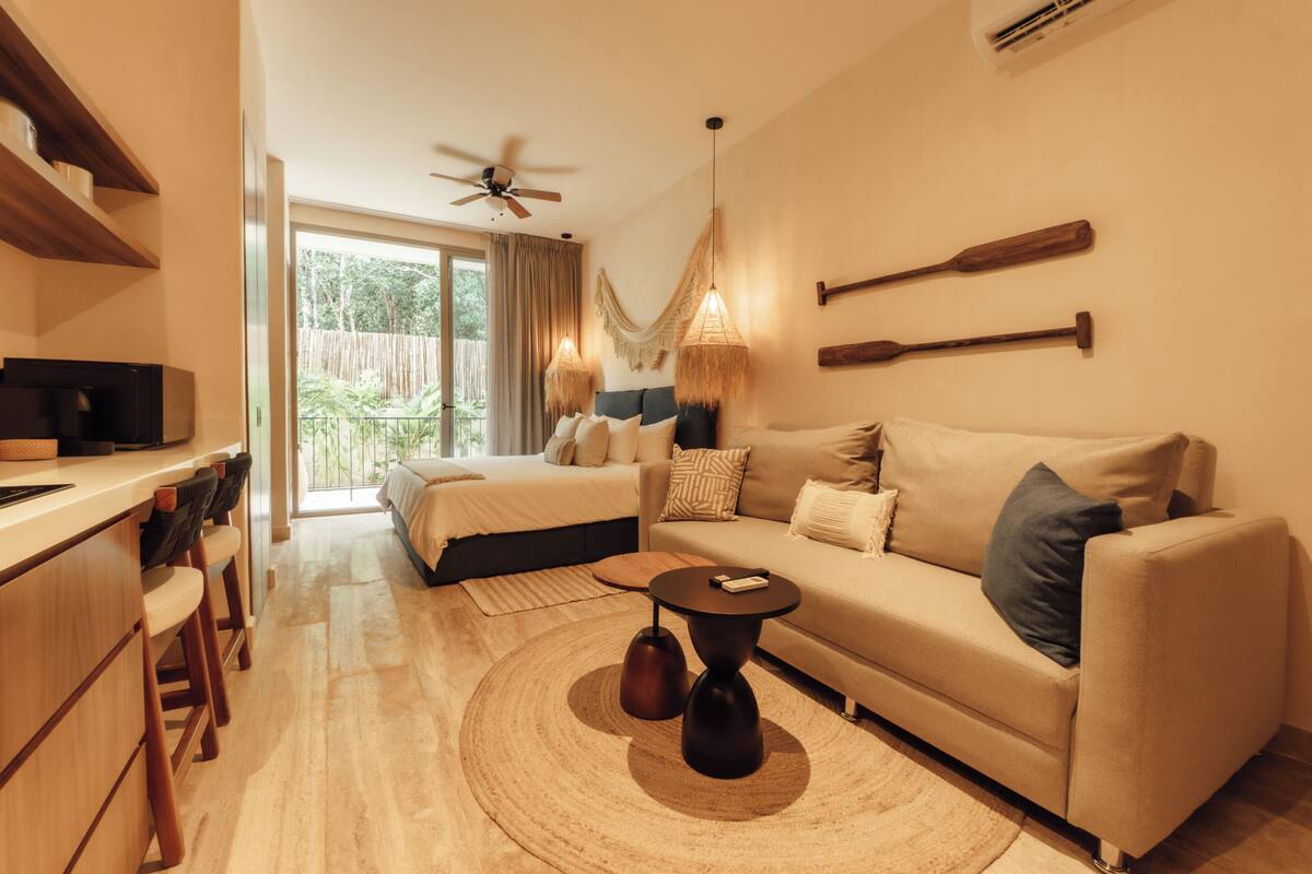 Une chambre d’hôtel moderne équipée d’un lit, d’un canapé, d’un bureau et d’un coin bar.