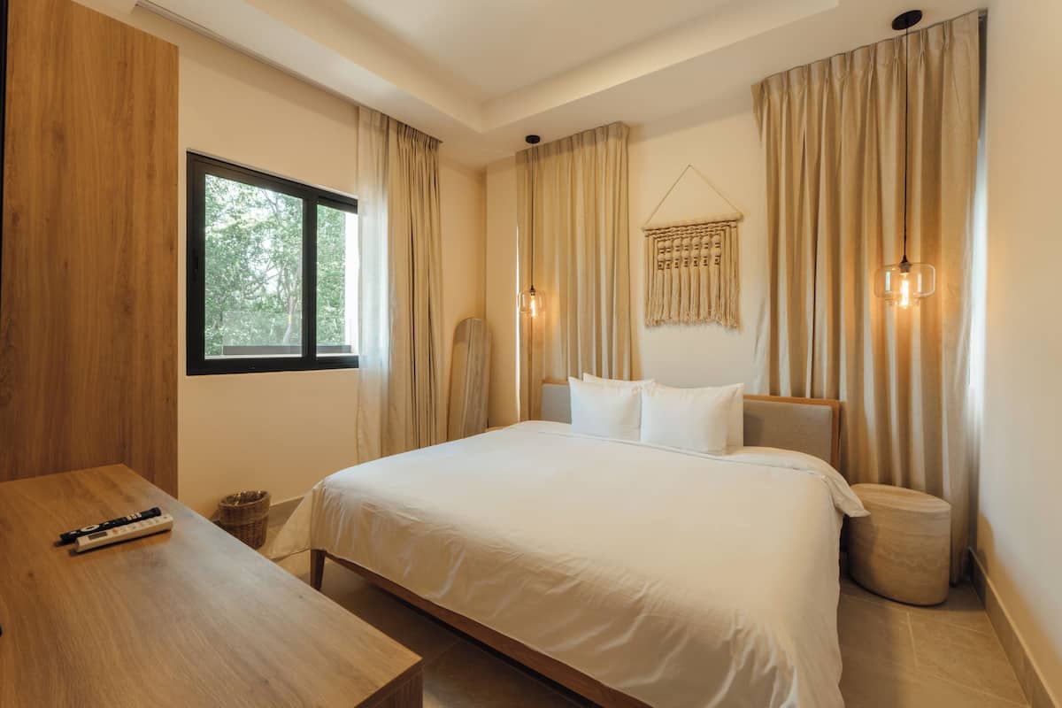 Une chambre avec un grand lit, un bureau en bois et une fenêtre.