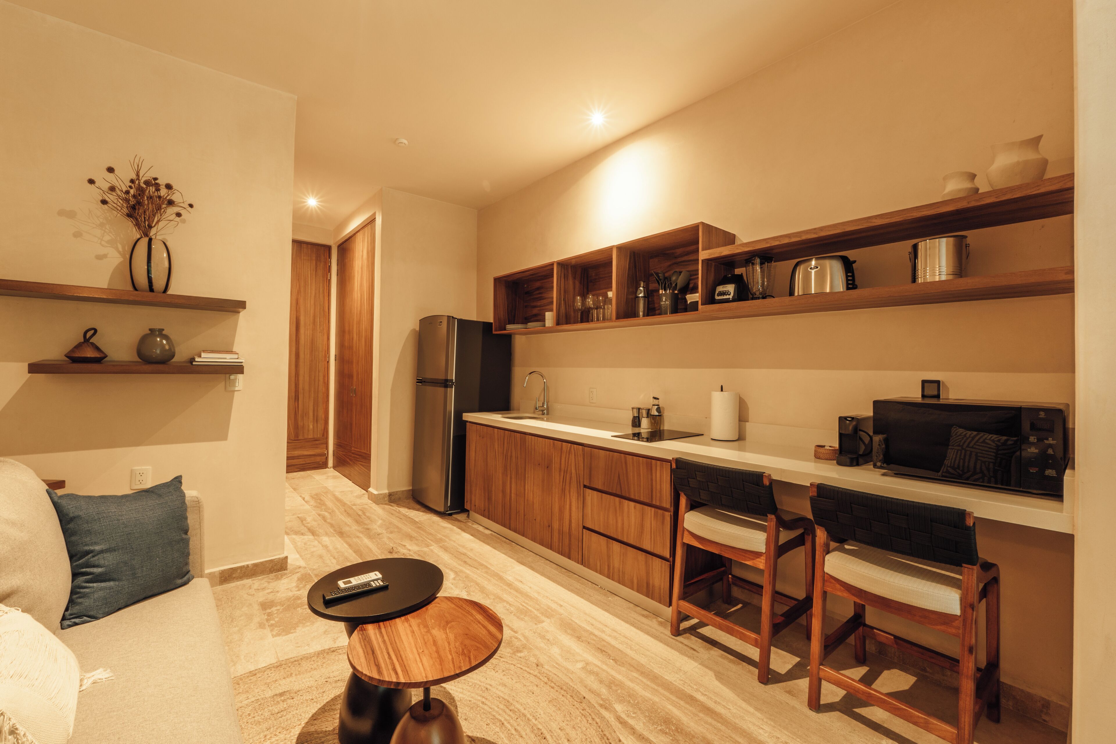 Een moderne keuken met houten kastjes, een inbouwoven en een eethoek met barstoelen.