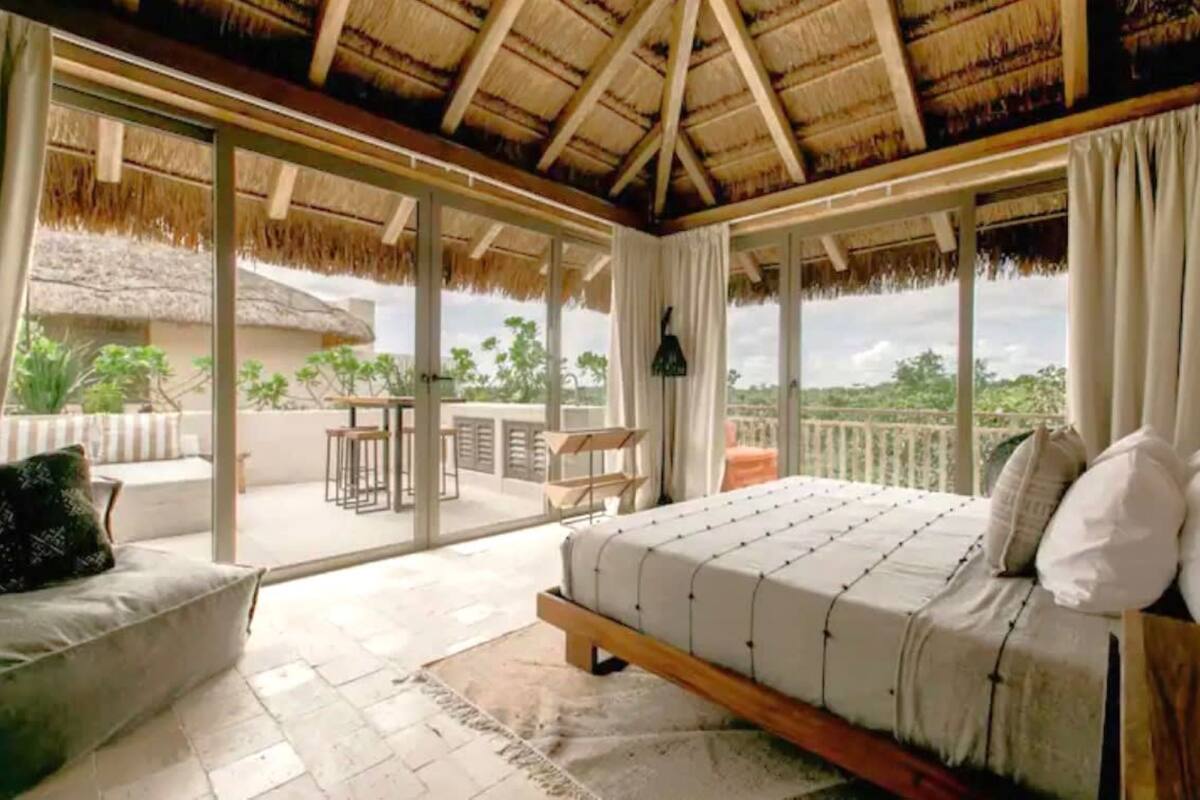 Une chambre avec un grand lit, un canapé et un balcon offrant une vue sur le paysage.