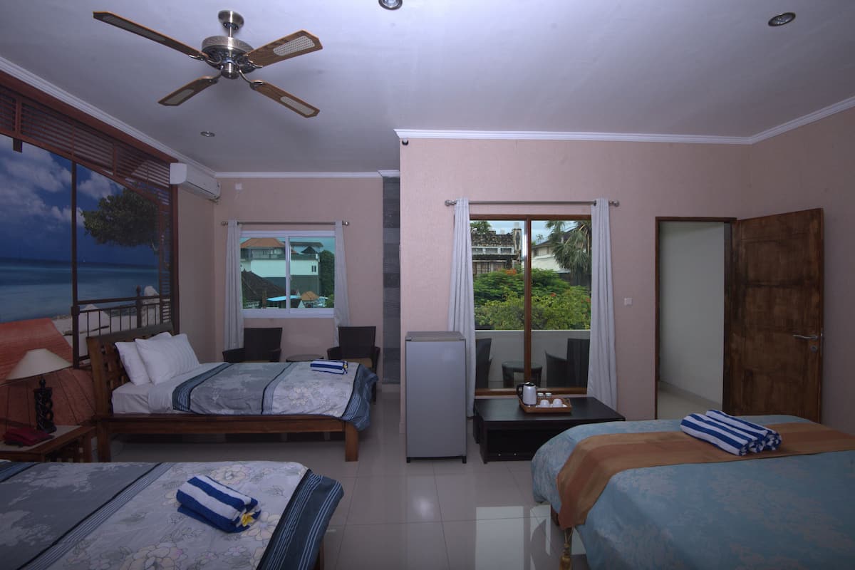 Habitación de hotel con dos camas, ventilador de techo, refrigerador, mesa de comedor y vistas al exterior.