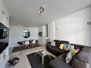 A modern living room with a sofa, coffee table, and dining area.