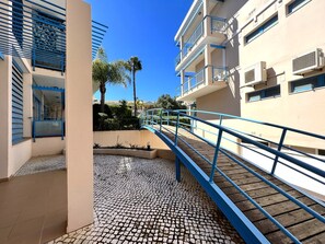 A building with a tiled patio area, a blue railing, and a clear blue sky.