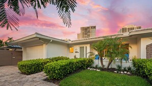A modern hotel with a paved driveway, manicured lawns, and a view of tall buildings in the background. - Heated Pool Waterfront Retreat – A Fun, Sun-Soaked Florida Getaway on the Waterway Escape Now! (Fort Lauderdale)