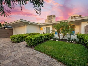 A modern hotel with a paved driveway, manicured lawns, and a view of tall buildings in the background. - Heated Pool Waterfront Retreat – A Fun, Sun-Soaked Florida Getaway on the Waterway Escape Now! (Fort Lauderdale)