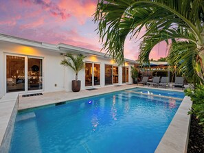 A swimming pool with a view of a house and palm trees. - Heated Pool Waterfront Retreat – A Fun, Sun-Soaked Florida Getaway on the Waterway Escape Now! (Fort Lauderdale)