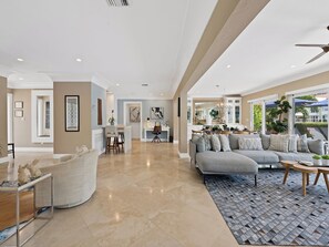 A spacious living room with a large gray sofa, a coffee table, and a patterned rug. - Heated Pool Waterfront Retreat – A Fun, Sun-Soaked Florida Getaway on the Waterway Escape Now! (Fort Lauderdale)