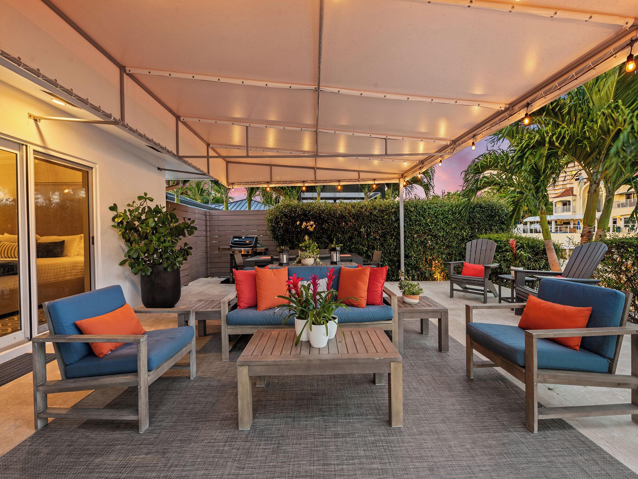 An outdoor patio with seating, a table, and a large potted plant.