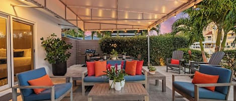 Un patio al aire libre con asientos, una mesa y una planta grande en maceta.