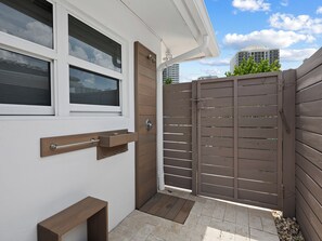 A gated entrance with a wooden door and a metal handle, a small wooden bench, and a tiled patio area. - Heated Pool Waterfront Retreat – A Fun, Sun-Soaked Florida Getaway on the Waterway Escape Now! (Fort Lauderdale)