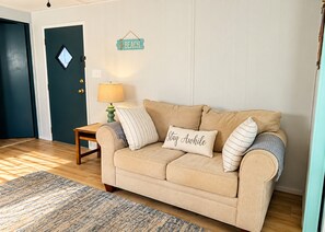 Un salon chaleureux avec un canapé beige, une petite table avec une lampe et un tapis.