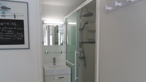 Une salle de bain avec une douche à parois de verre, un lavabo blanc et un miroir au-dessus du lavabo.