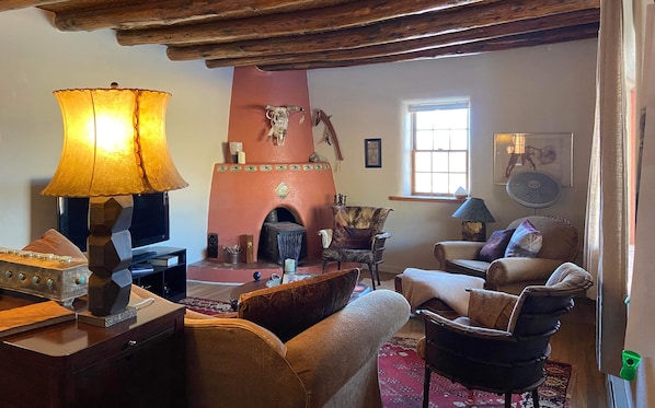 A cozy living room with a fireplace, wooden ceiling beams, and a comfortable seating area.