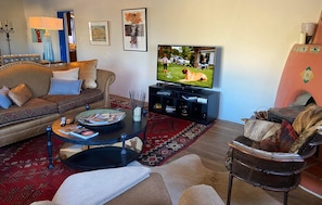 A living room with a sofa, a coffee table, a TV, and a fireplace.