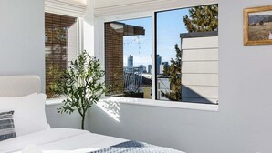 Un dormitorio con un ventanal grande, una cama y una planta en maceta.