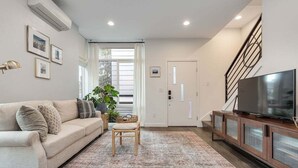 Una sala de estar con un sofá, un televisor y una escalera.