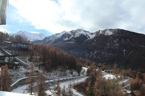 Un paysage de montagne avec une route et un bâtiment doté d’une façade en verre.