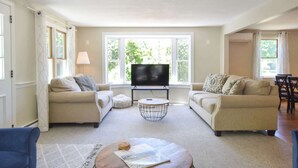 A living room with two sofas, a coffee table, a TV, and large windows. - 4 Mins to Bayside Beaches! (Eastham)