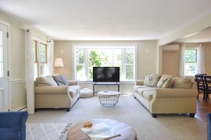 A living room with two sofas, a coffee table, a TV, and large windows.