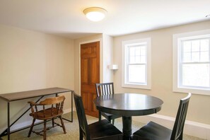 A room with a round table, four chairs, a wooden door, and two windows. - Minutes to Oceanside Beaches! (Eastham)