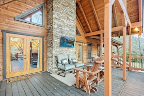Eine Holzterrasse mit Sitzgelegenheiten im Freien, Steinmauern und einem großen Fenster.