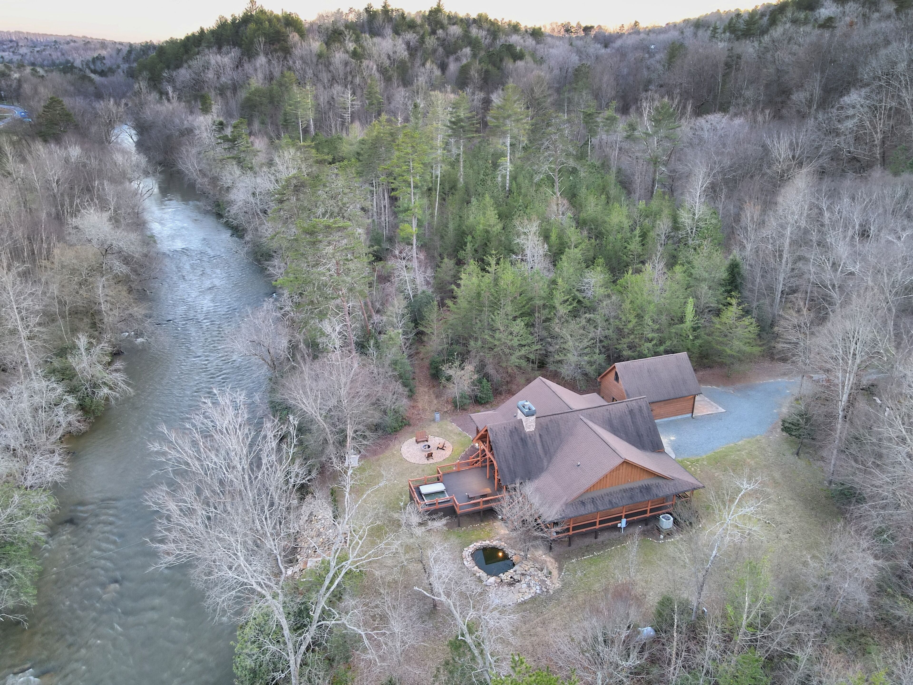 A cabin with a pond, surrounded by dense forest and a river.
