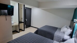 Una habitación de hotel con dos camas, televisión, baño y puerta que da a otra habitación.