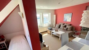 A compact living space with a bed, a sofa, a coffee table, and a lamp. - Clason vacation apartment with sea view (Heringsdorf)