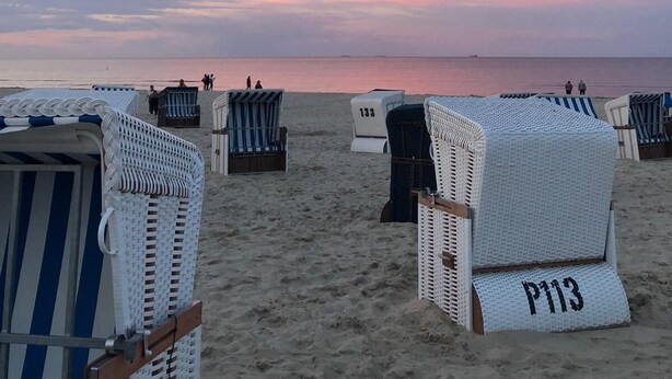 Beach chairs with numbers P113 and P133 on a sandy beach with a calm sea and a pink sky. - Clason vacation apartment with sea view (Heringsdorf)