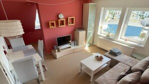 A compact living space with a TV, sofa, and dining area. - Clason vacation apartment with sea view (Heringsdorf)