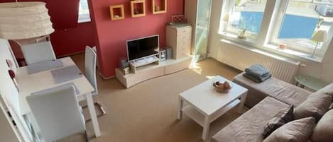 A compact living space with a TV, sofa, and dining area.
