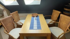 A dining area with a wooden table and wicker chairs, a hanging light fixture, and skylights. - Clason vacation apartment with sea view (Heringsdorf)