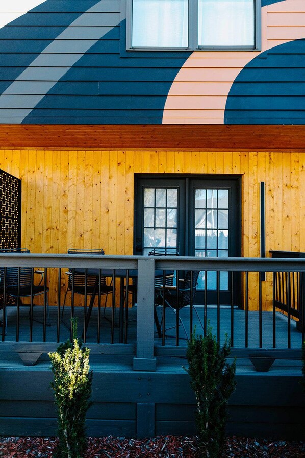 A modern building with a wooden facade, large windows, and outdoor seating.