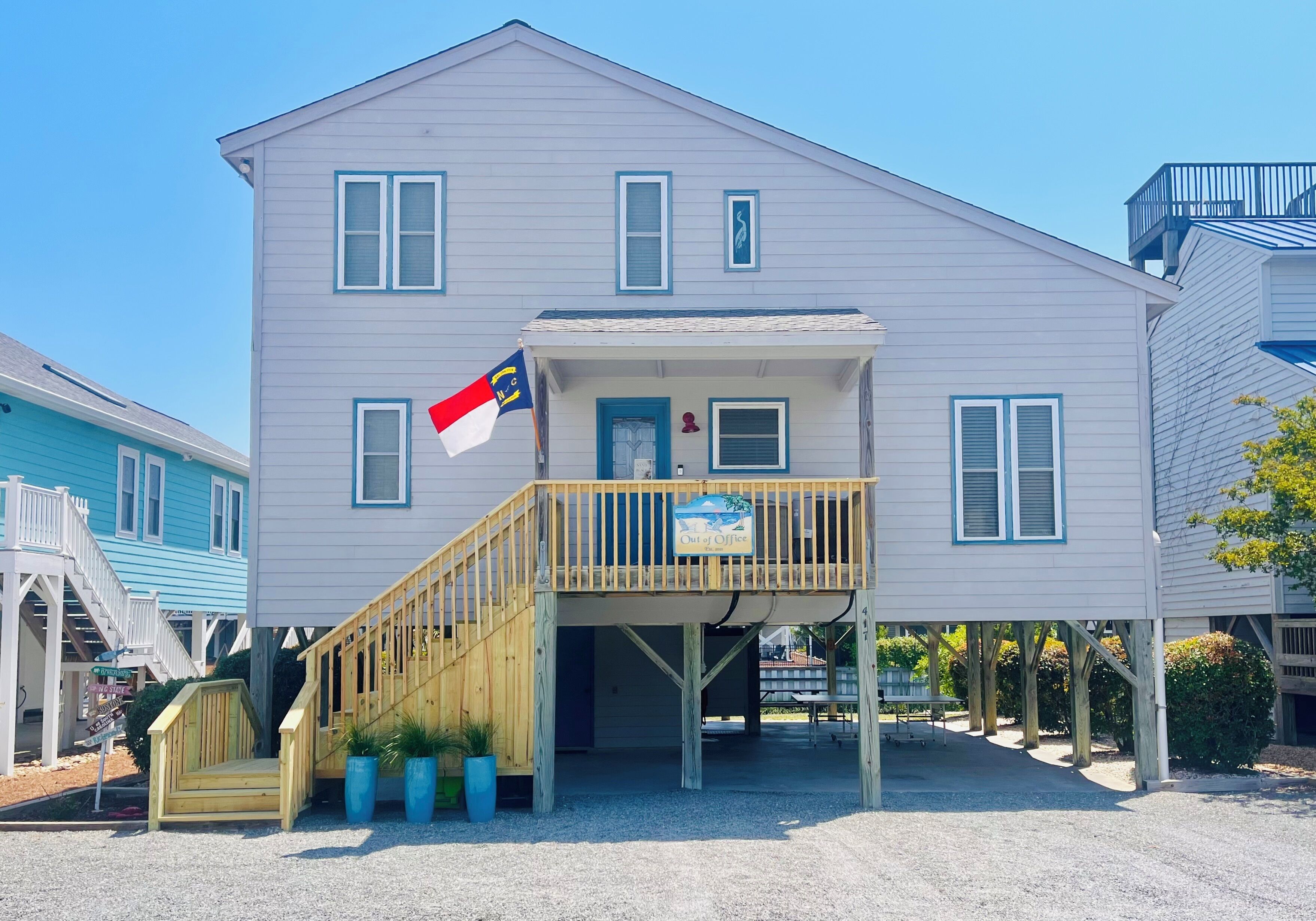 A two-story building with a wooden deck, a flag, and a sign that reads 'Out of Office.'