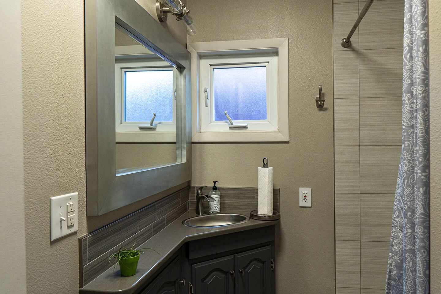 A bathroom with a sink, mirror, and window.
