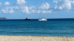 Una playa arenosa con dos barcos en el agua.