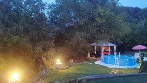 Un jardin avec une piscine, un petit kiosque et un espace bien éclairé.