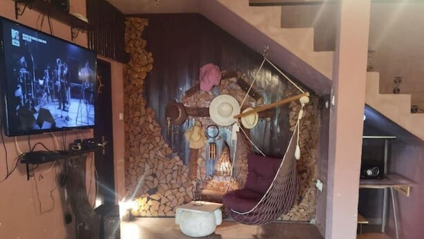 Un salon chaleureux avec un mur en pierre, un fauteuil suspendu, un téléviseur à écran plat et une petite table.
