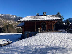 A wooden cabin with a snow-covered roof, situated on a snowy slope with a mountainous backdrop. - Chalet Alpen, 5 bedrooms, sauna, near Megève and the ski slopes. (Praz-sur-Arly)