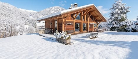A wooden cabin with a sloped roof, large windows, and a covered porch area.
