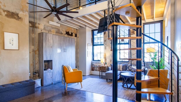 Un loft espacioso con techos altos a la vista, una escalera espiral y una decoración que combina lo moderno y lo industrial.