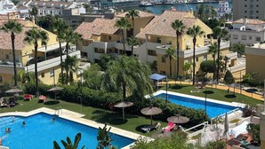 Un complexe hôtelier doté d’une piscine, de palmiers et offrant une vue sur l’océan.